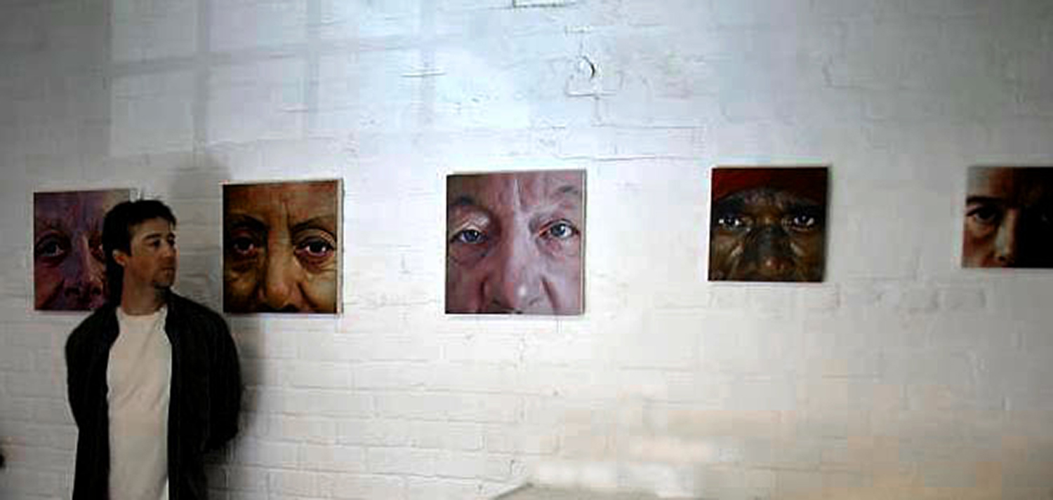 the artist standing next to 5 of his portrait paintings in 2005